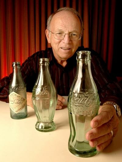 Phil Mooney, director of Archives for The Coca-Cola Company, shows one of the two remaining original contour bottles and displays earlier prototypes